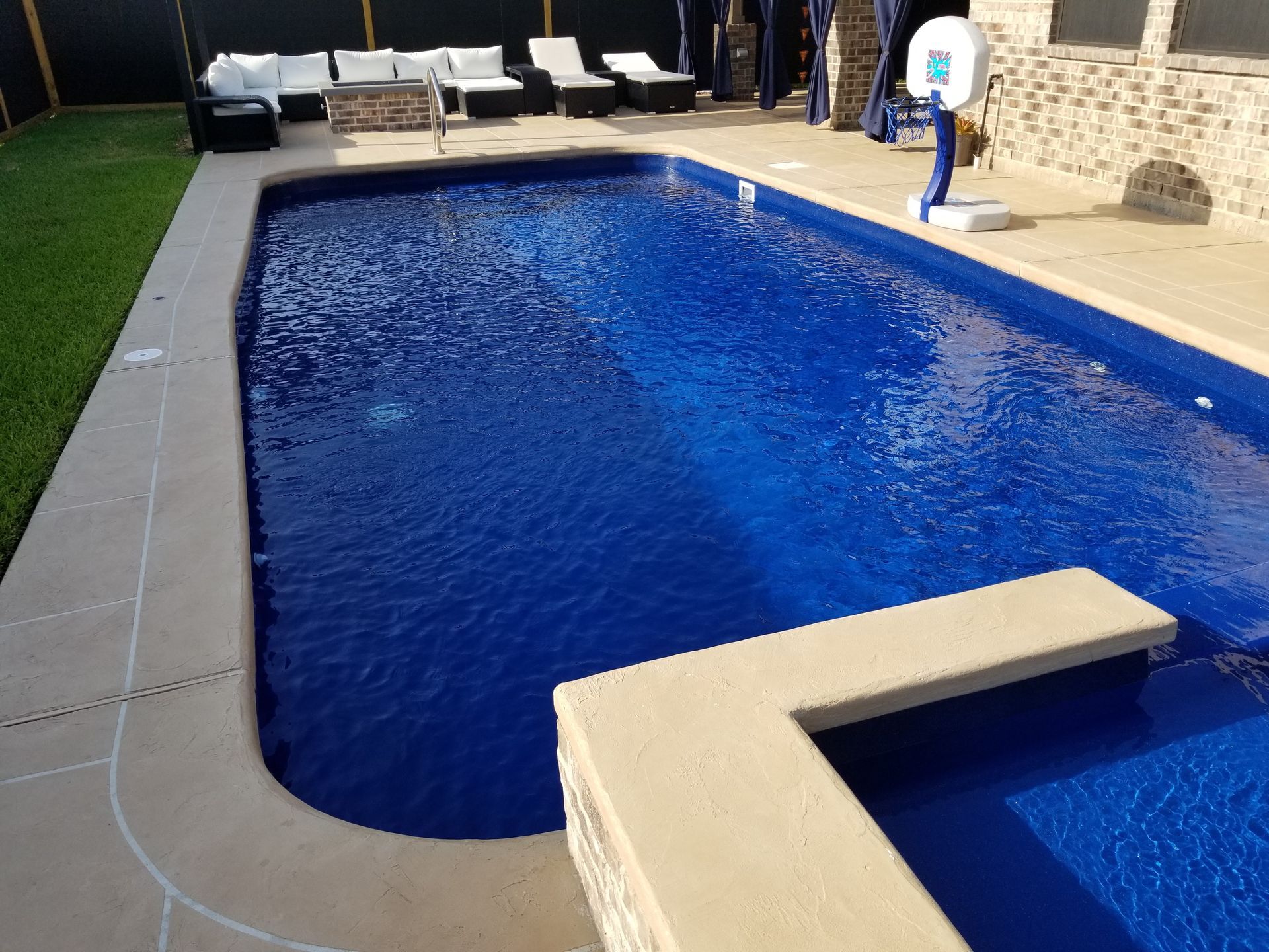 A large swimming pool with a basketball hoop in the backyard