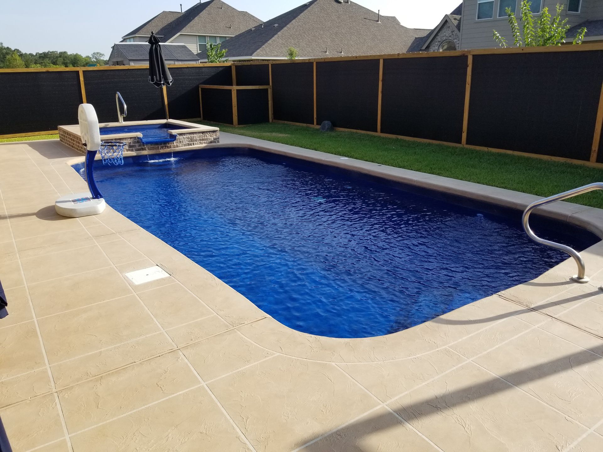 A large swimming pool in a backyard with a black fence surrounding it.