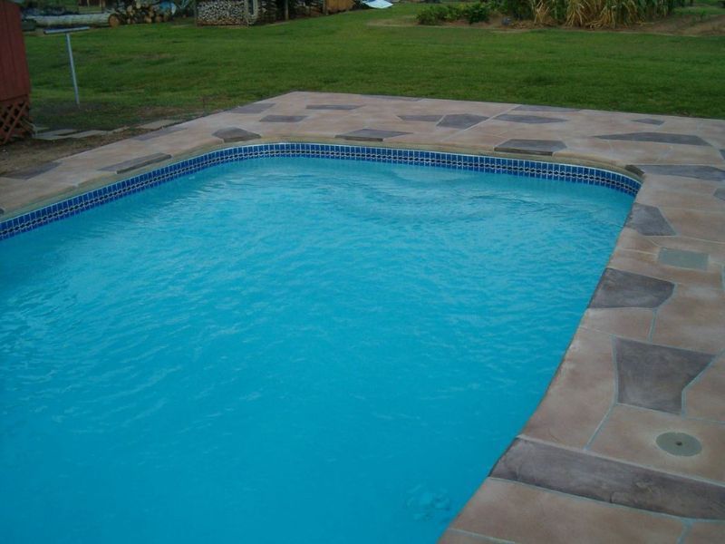 A large swimming pool filled with blue water is surrounded by grass.