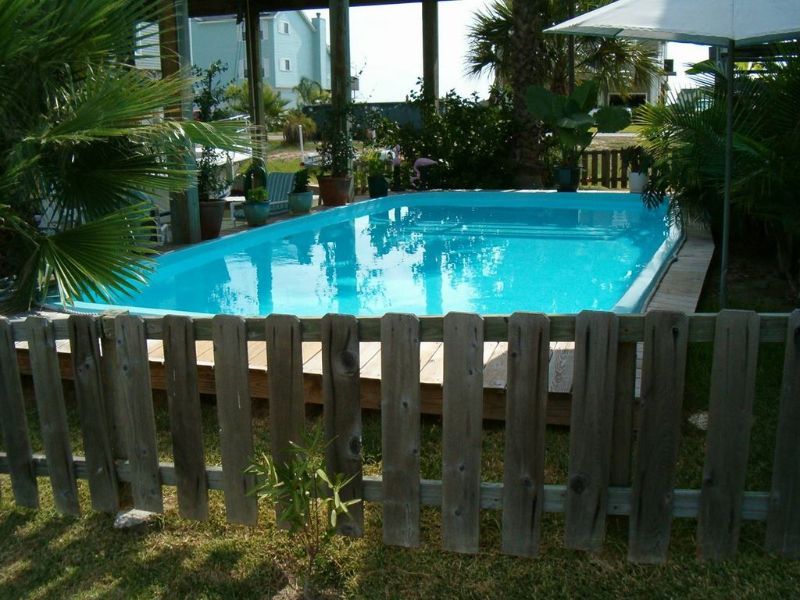 A large swimming pool is behind a wooden fence