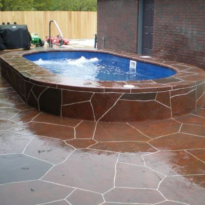 A large swimming pool is surrounded by a stone patio