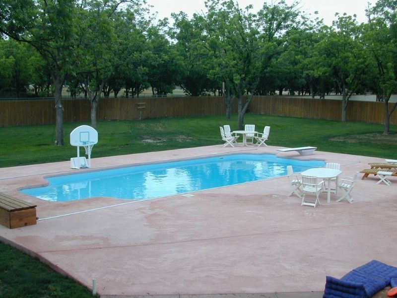 A large swimming pool with a basketball hoop in the backyard