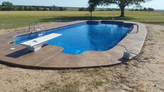 A large swimming pool with a diving board in the middle of it.