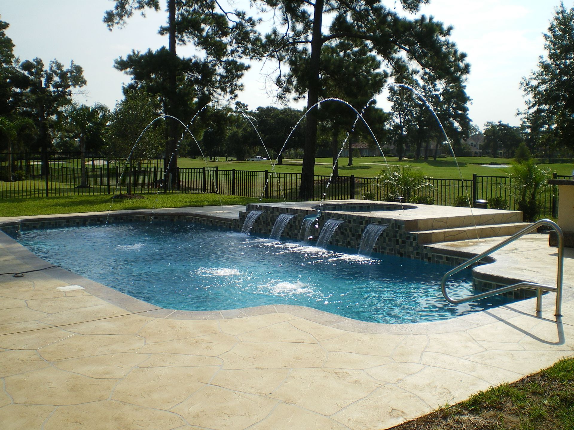 A large swimming pool with a fountain in front of a house