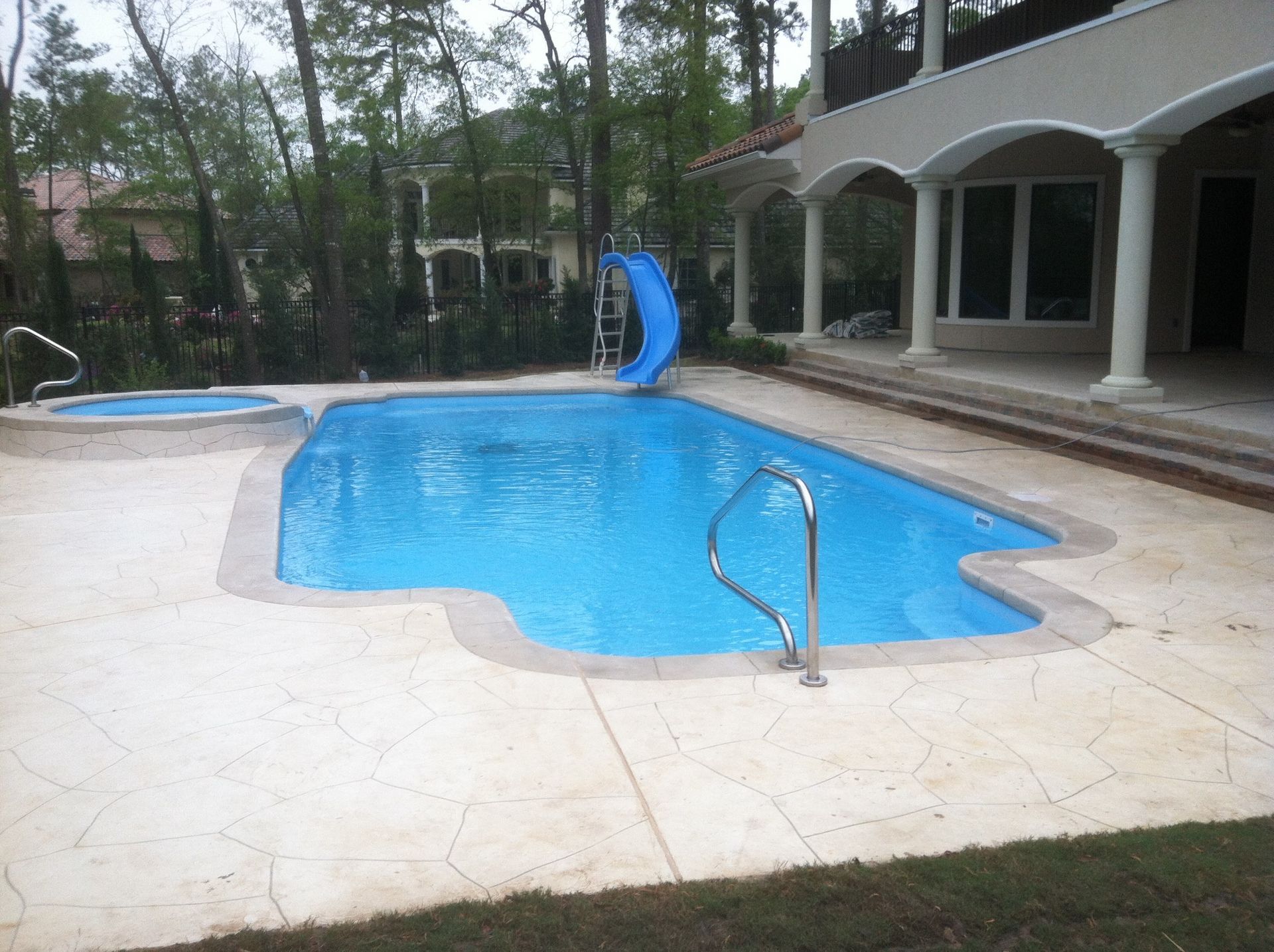A large swimming pool with a slide in the backyard of a house