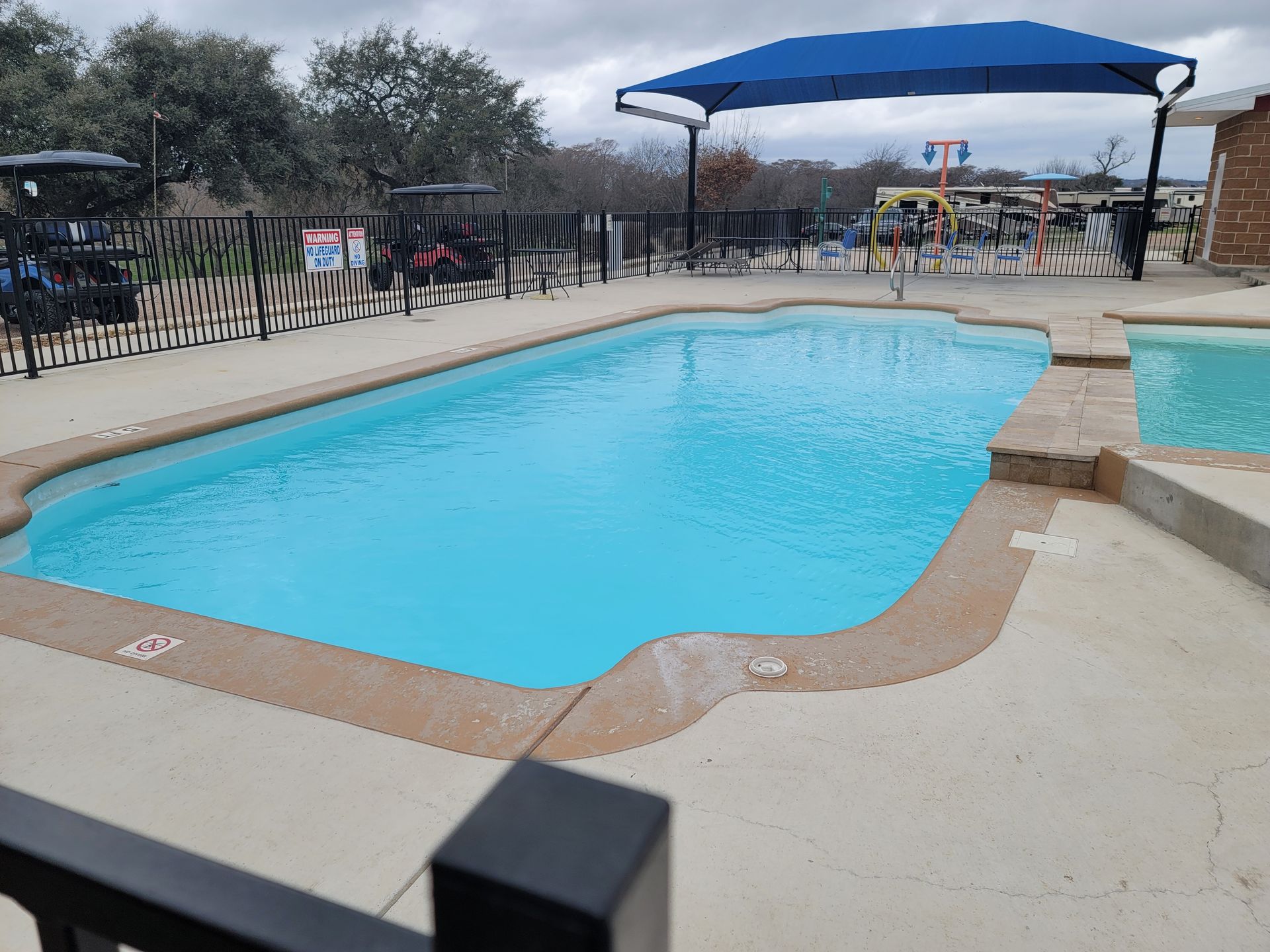 A large swimming pool with a blue umbrella over it.