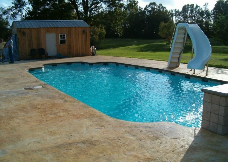 A swimming pool with a slide and a shed in the background
