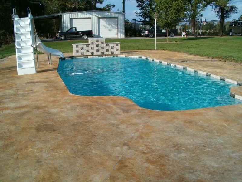 A large swimming pool with a slide in the backyard