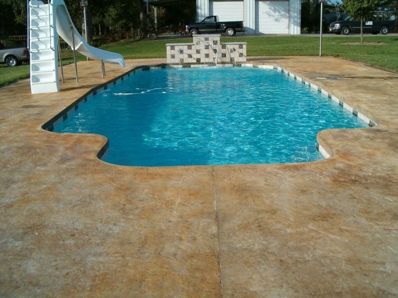 A large swimming pool with a slide in the backyard