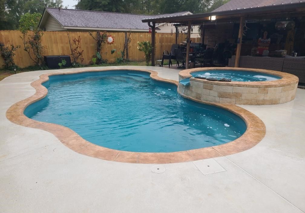 A large swimming pool with a hot tub in the backyard of a house.