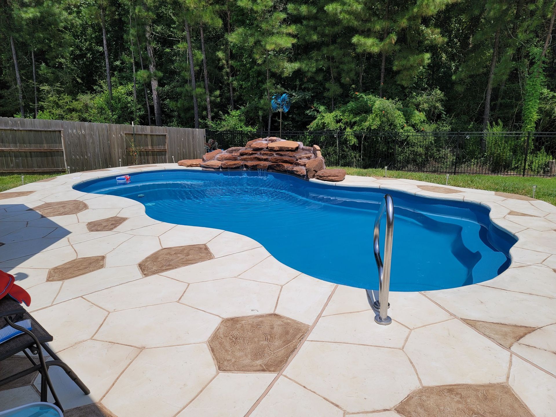 A large swimming pool with a waterfall in the backyard