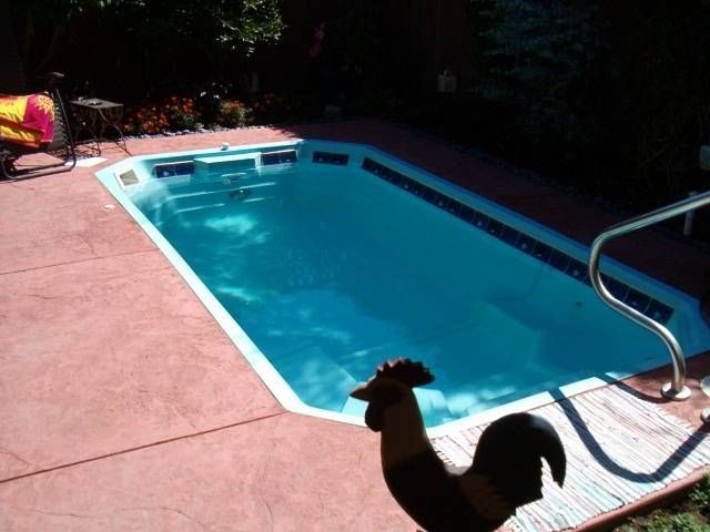 A statue of a rooster stands in front of a swimming pool