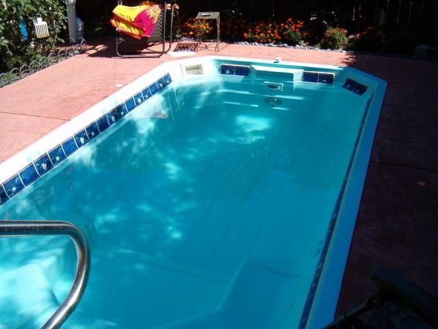 A large swimming pool with blue tiles and a metal railing