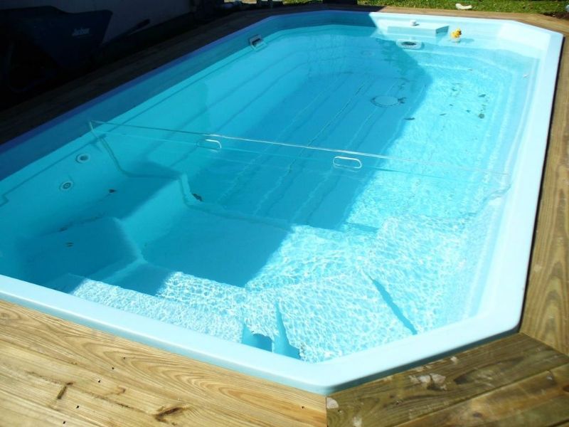 A large swimming pool is sitting on top of a wooden deck.