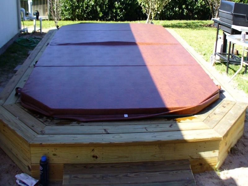 A wooden deck with a hot tub cover on it