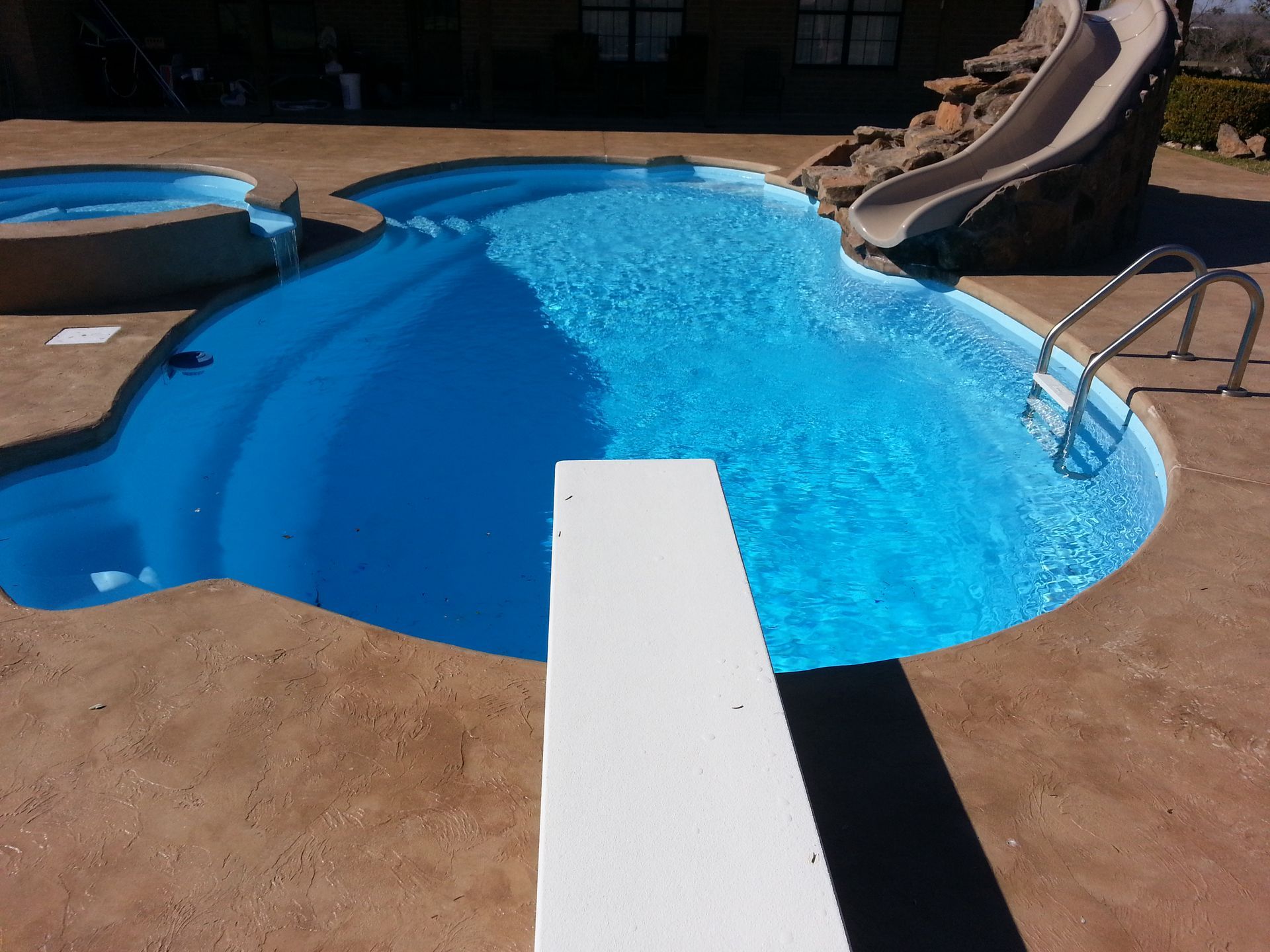 A swimming pool with a slide and a diving board