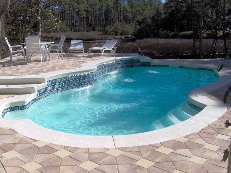 A large swimming pool surrounded by chairs and a table