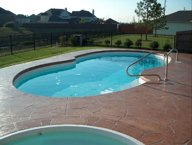 A swimming pool with a hot tub next to it