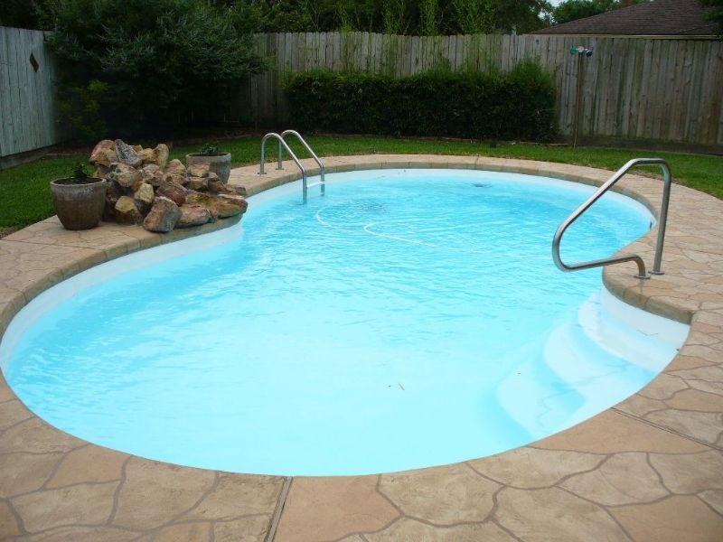 A swimming pool with stairs and a fence in the background