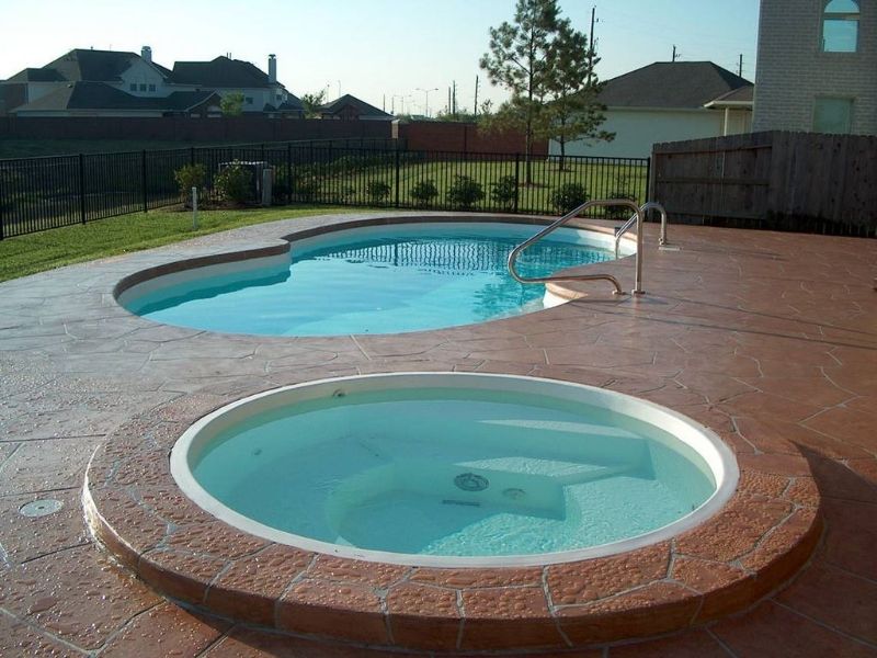 A hot tub sits next to a large swimming pool