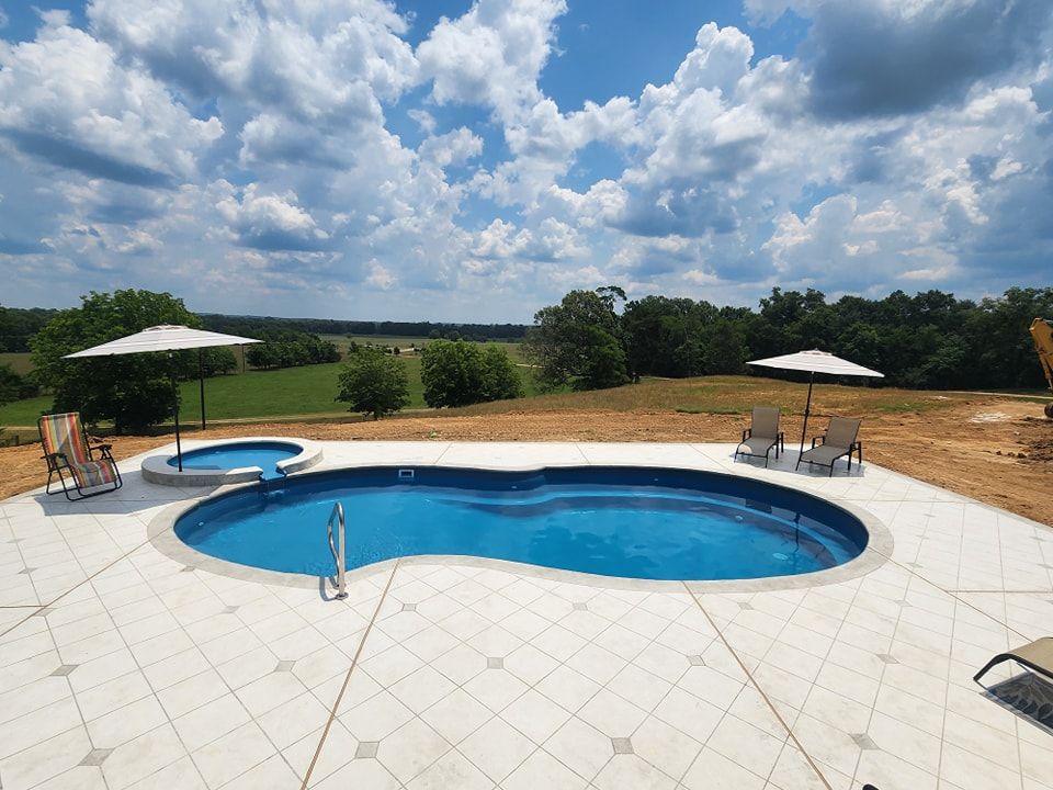 A large swimming pool surrounded by chairs and umbrellas on a sunny day.