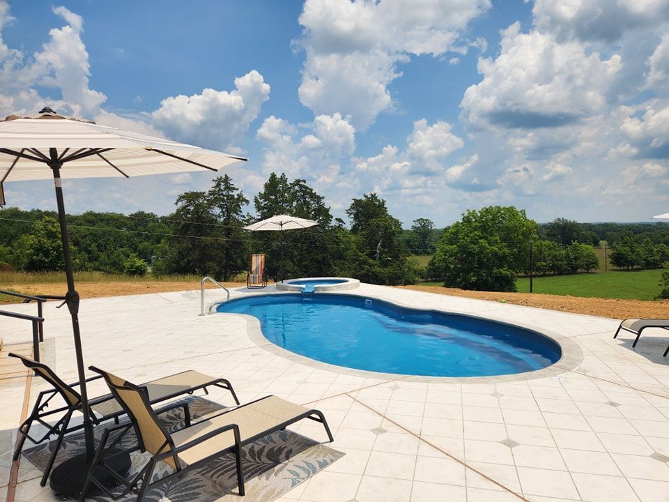 A large swimming pool surrounded by chairs and umbrellas on a sunny day
