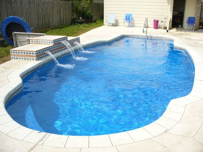 A large swimming pool with a waterfall in the backyard