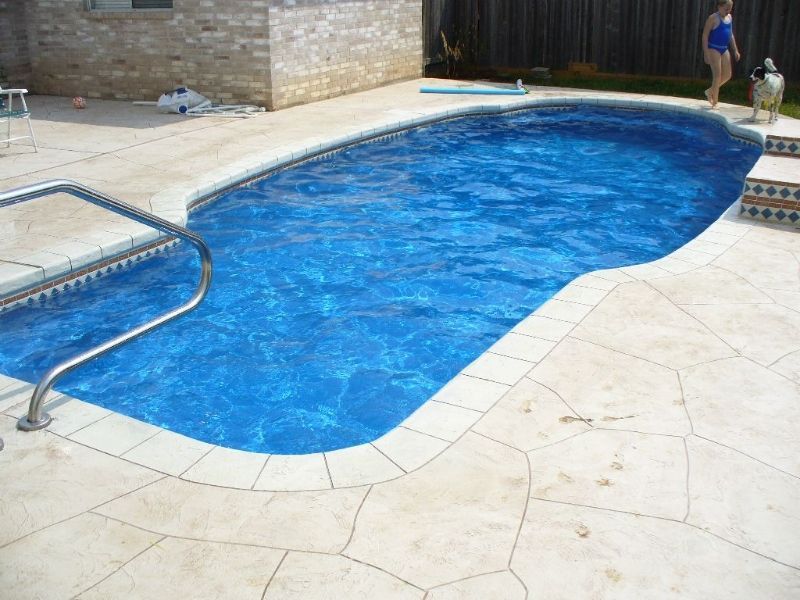 A woman in a blue bathing suit is standing next to a swimming pool