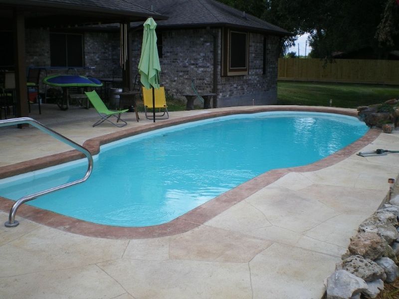 A large swimming pool with a green umbrella in front of a house