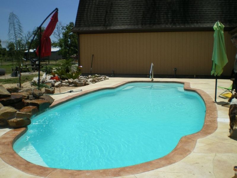 A large swimming pool with a green umbrella in front of it