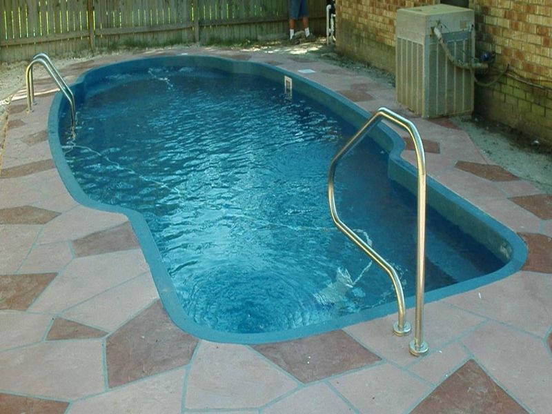 A swimming pool with stairs and a fence in the background