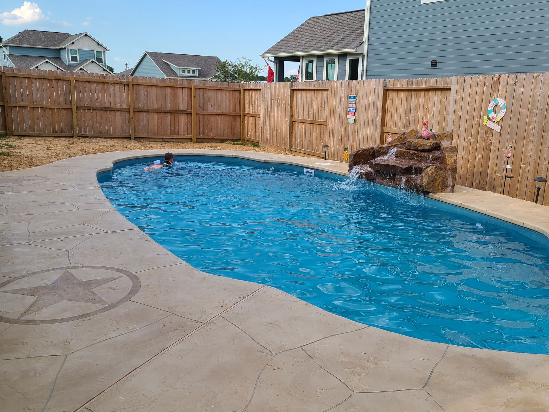 A large swimming pool with a waterfall in the backyard of a house