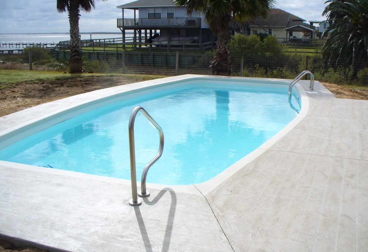 A large swimming pool with a house in the background