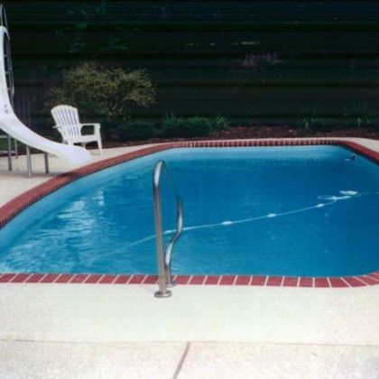 A swimming pool with a slide and chairs in the background