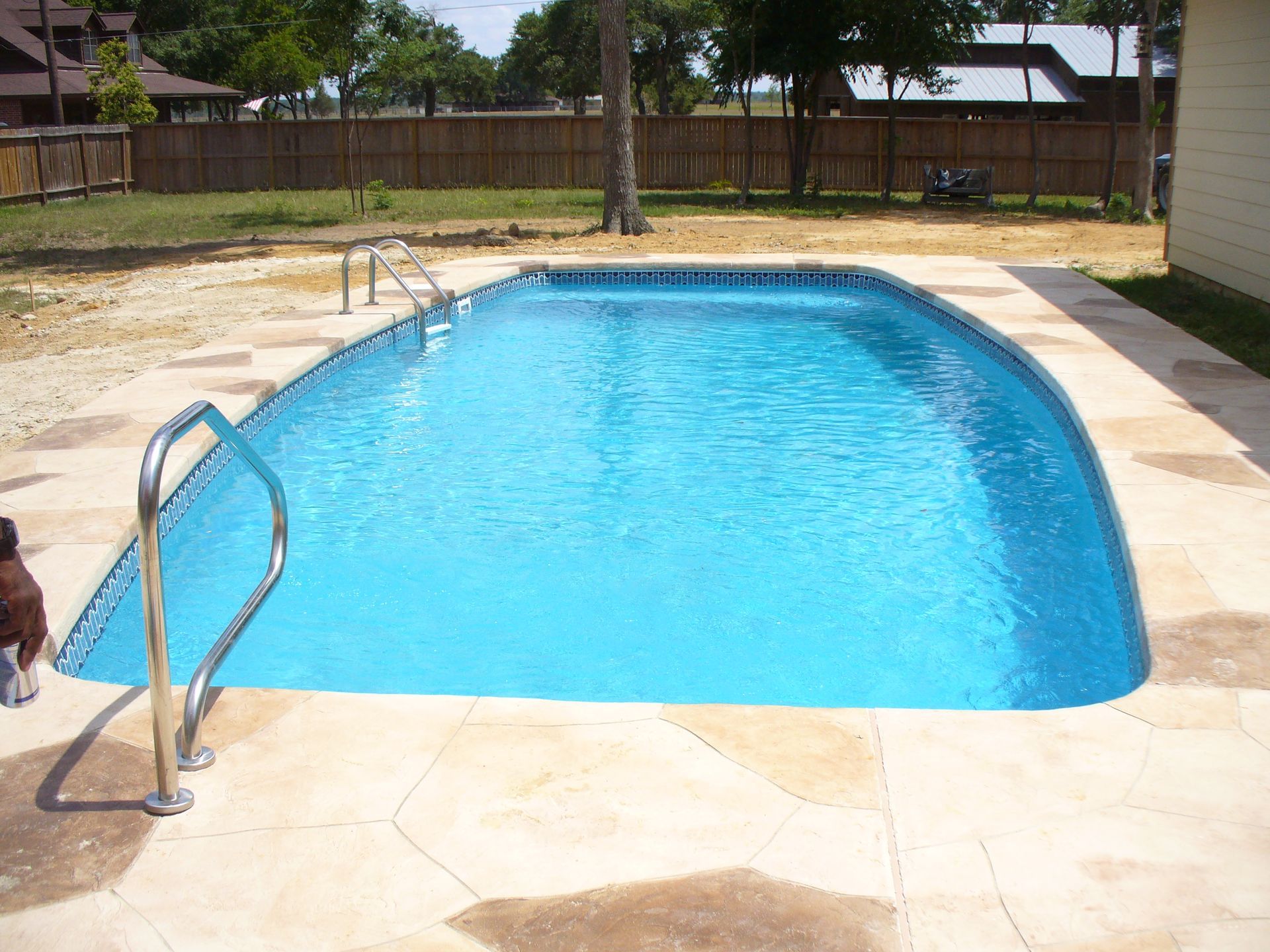 There is a large swimming pool in the backyard of a house.