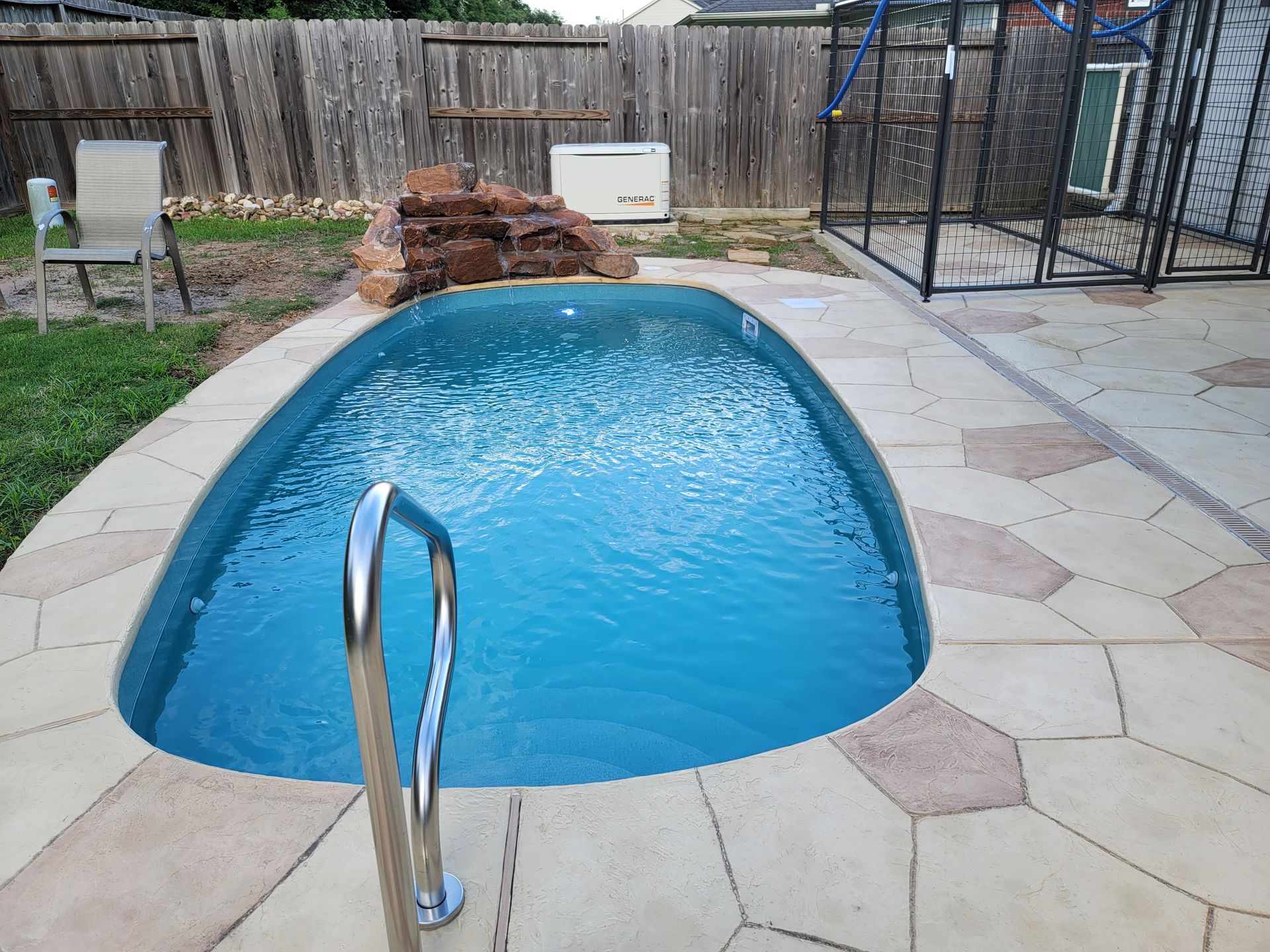 A small swimming pool with stairs leading to it in a backyard.