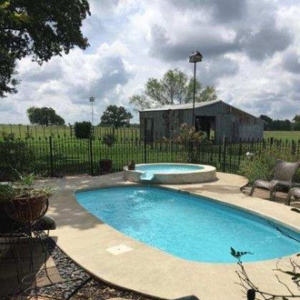 A large swimming pool with a hot tub in the backyard of a house.