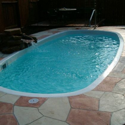 A large swimming pool is sitting on top of a tiled patio.