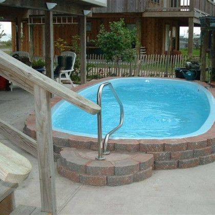 A swimming pool with stairs leading up to it in front of a house