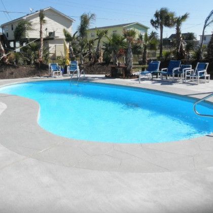 A large swimming pool surrounded by chairs and palm trees