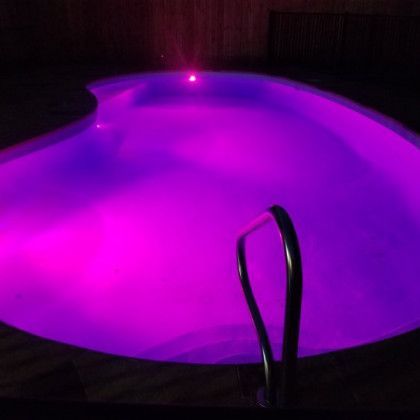 A swimming pool is lit up with purple lights at night.