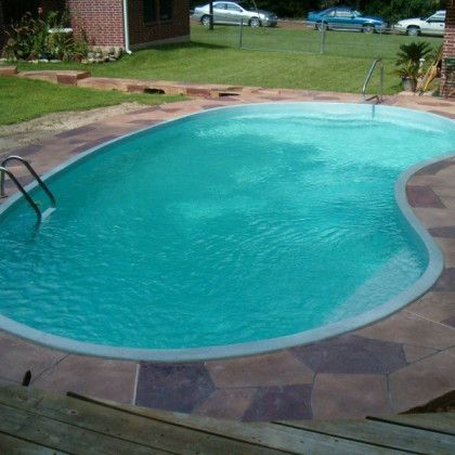 A large swimming pool in a backyard with cars parked in the background