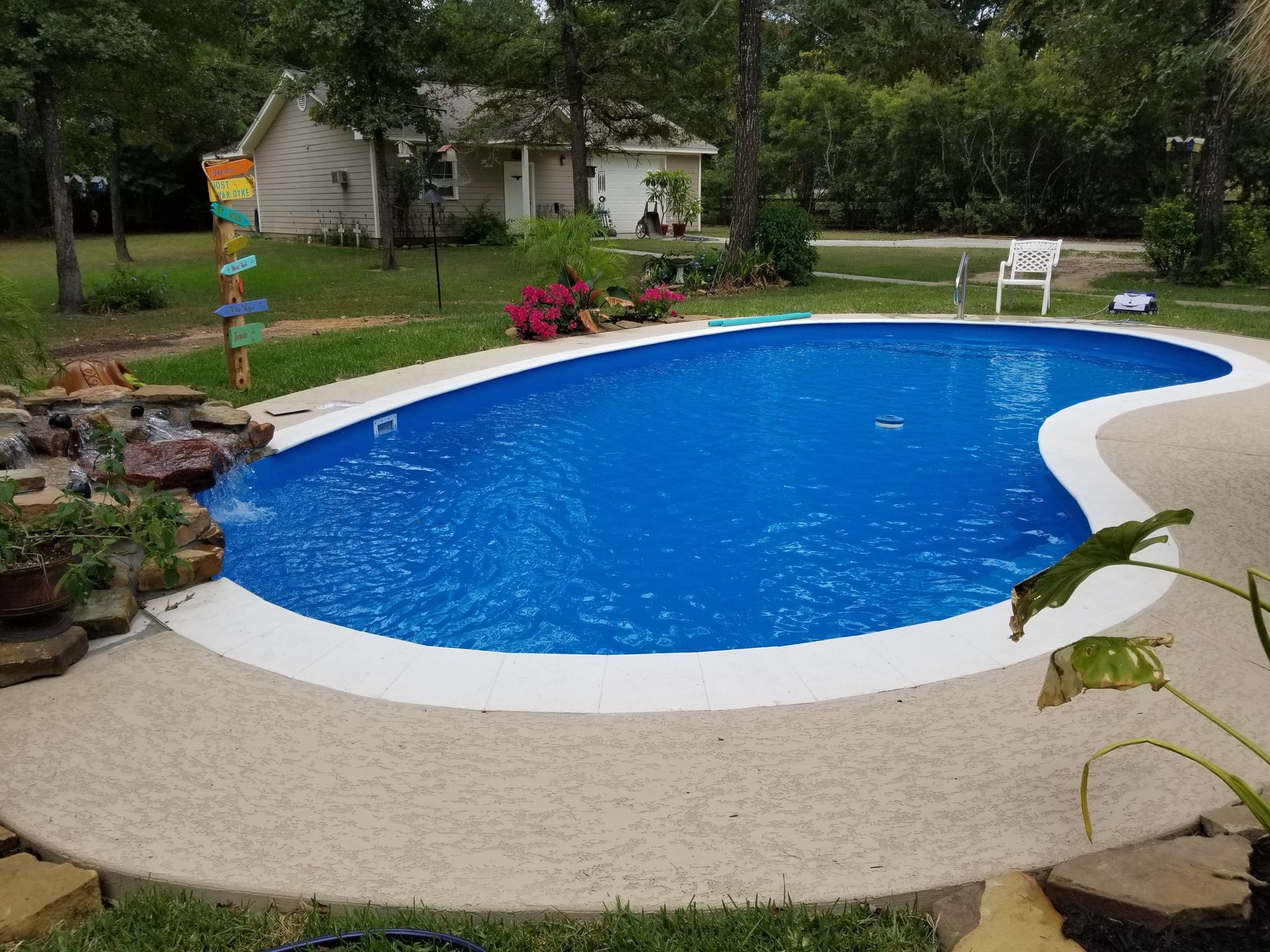 A large blue swimming pool is in the backyard of a house.