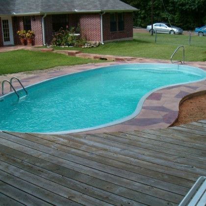 A large swimming pool in front of a brick house