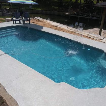 A large swimming pool is surrounded by chairs and umbrellas.