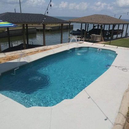 A large swimming pool with a boat dock in the background