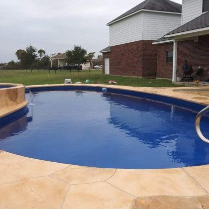 There is a large swimming pool in the backyard of a house.