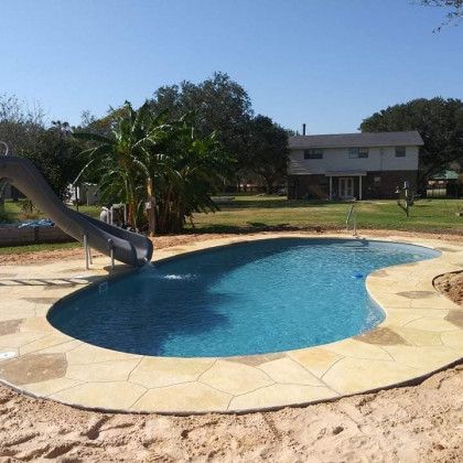 A swimming pool with a slide and a house in the background