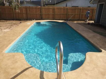 A large swimming pool with a wooden fence in the backyard.