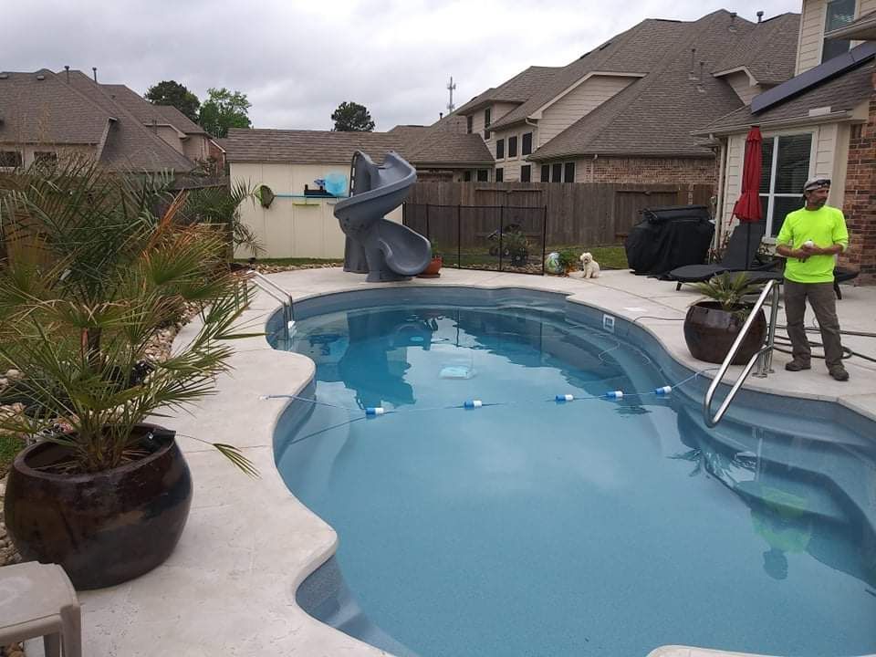A man in a yellow shirt is standing next to a swimming pool